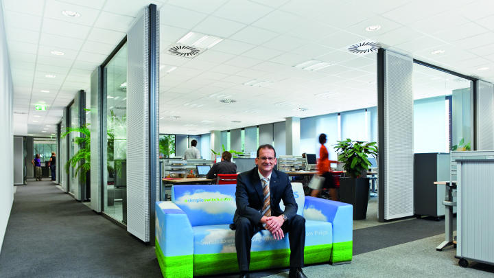 Man is sitting on the sky design couch on the corridor of Audi lit by Philips lighting