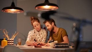"Stylish LED pendant lights casting warm glow over couple working together, showcasing energy-efficient illumination for productive evening tasks."