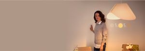 "Woman adjusting smart dimmer switch, controlling warm LED lighting ambiance in contemporary living space with minimalist d�cor"
